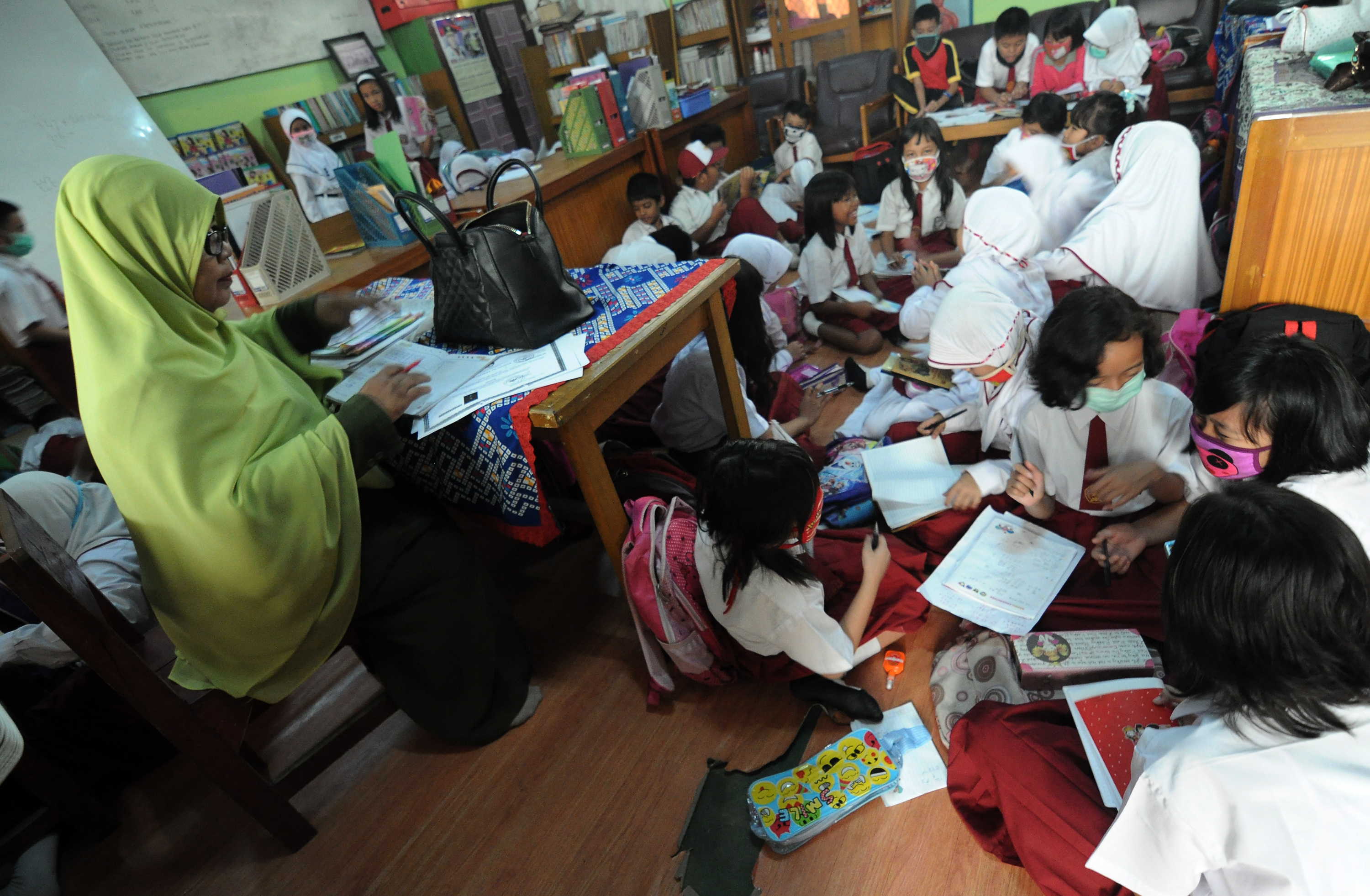 Beberapa pelajar SDN 77/IV Kota Jambi mengikuti kegiatan belajar mengajar sambil mengenakan masker didampingi guru mereka di Jambi.